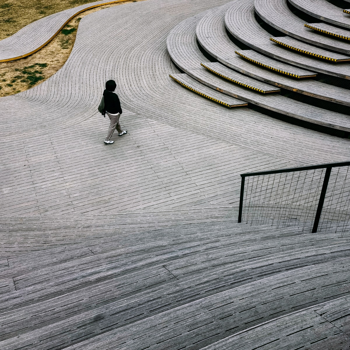 man in black jacket walking on gray concrete pathway during daytime